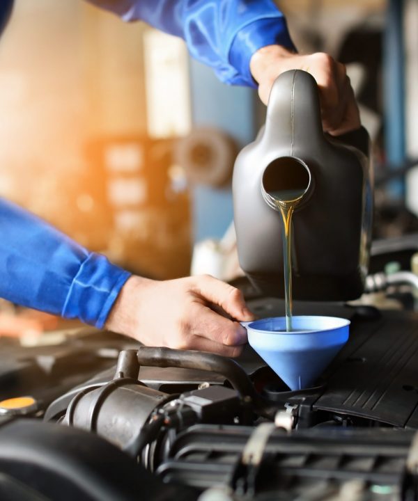 Male mechanic refilling car oil in service center