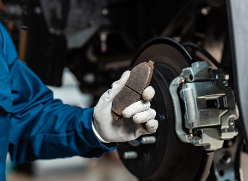 cropped view of mechanic holding brake pad near assembled disc brakes cropped view of mechanic holding brake pad near assembled disc brakes