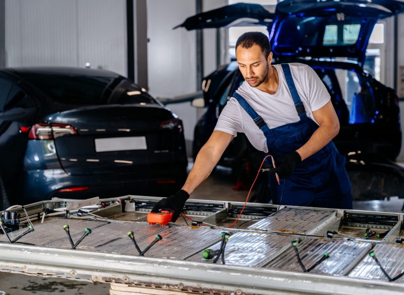 Arabian male technician engages with an EV Car Battery Cell Module troubleshooting a modern electric vehicle battery removed from the vehicle. Mechanic examining a car engine with voltmeter. Arabian male technician engages with an EV Car Battery Cell Module troubleshooting a modern electric vehicle battery removed from the vehicle. Mechanic examining a car engine with voltmeter.